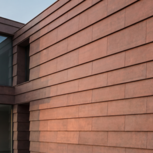 Tagsten_Dalarna_web - Klinker Made in Germany Modern red-brown brick-clad building with large glass windows overlooking a hillside at sunset-like light.
