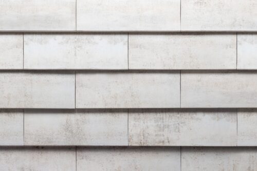Light gray concrete wall composed of horizontally arranged rectangular blocks with subtle weathering and shadows.